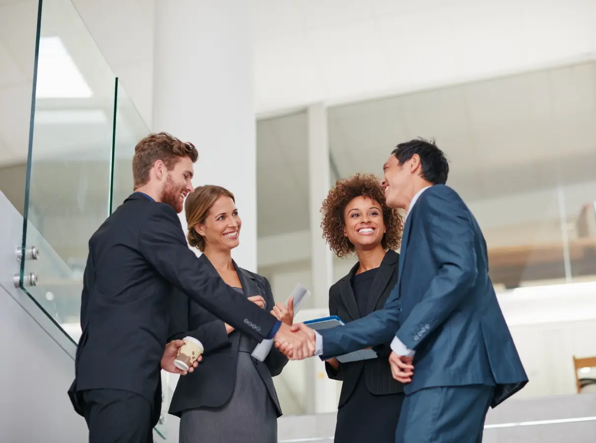 41 Four businesspeople shaking hands in an office.