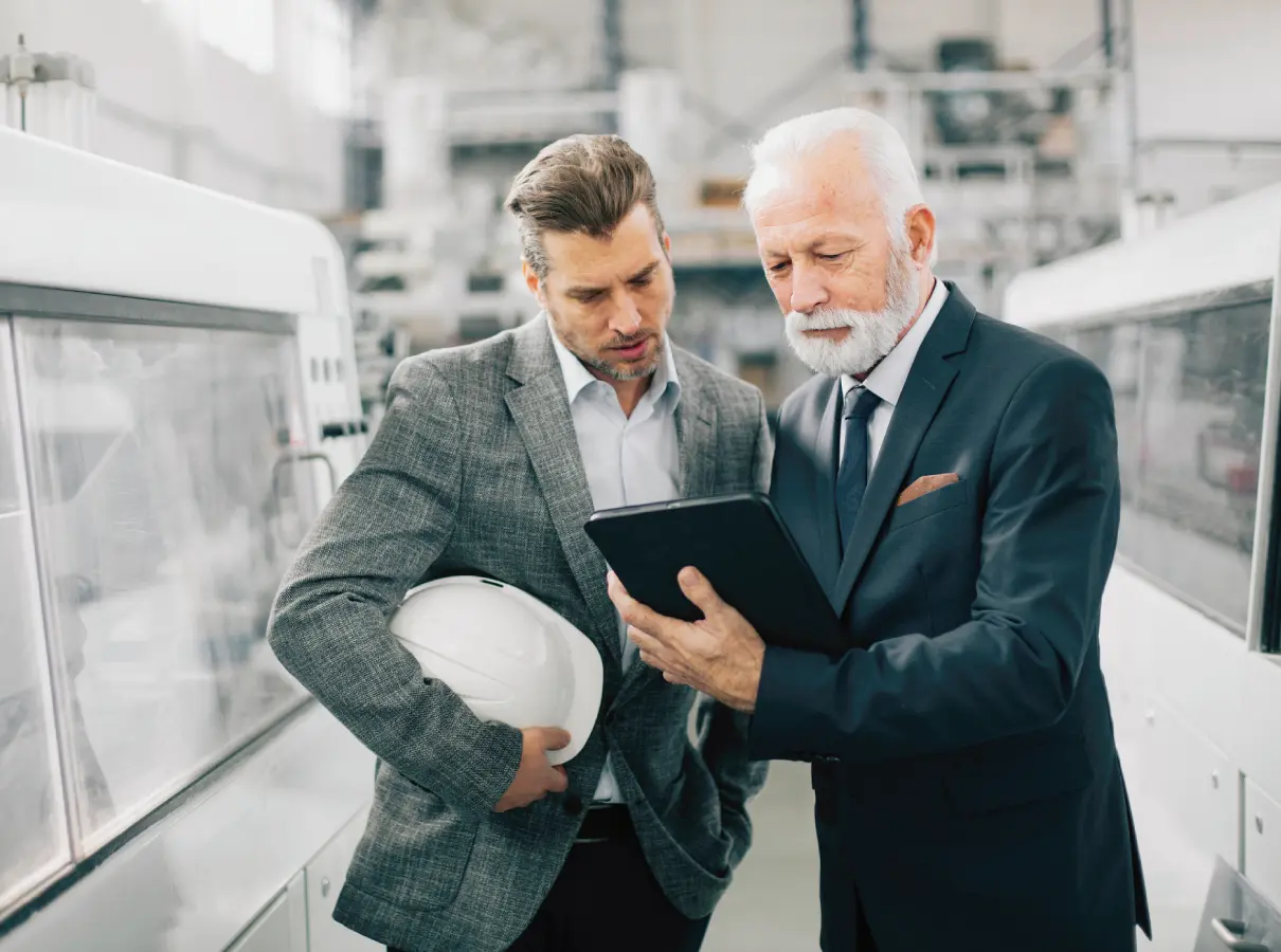 42 Two engineers reviewing plans on a tablet in a factory.