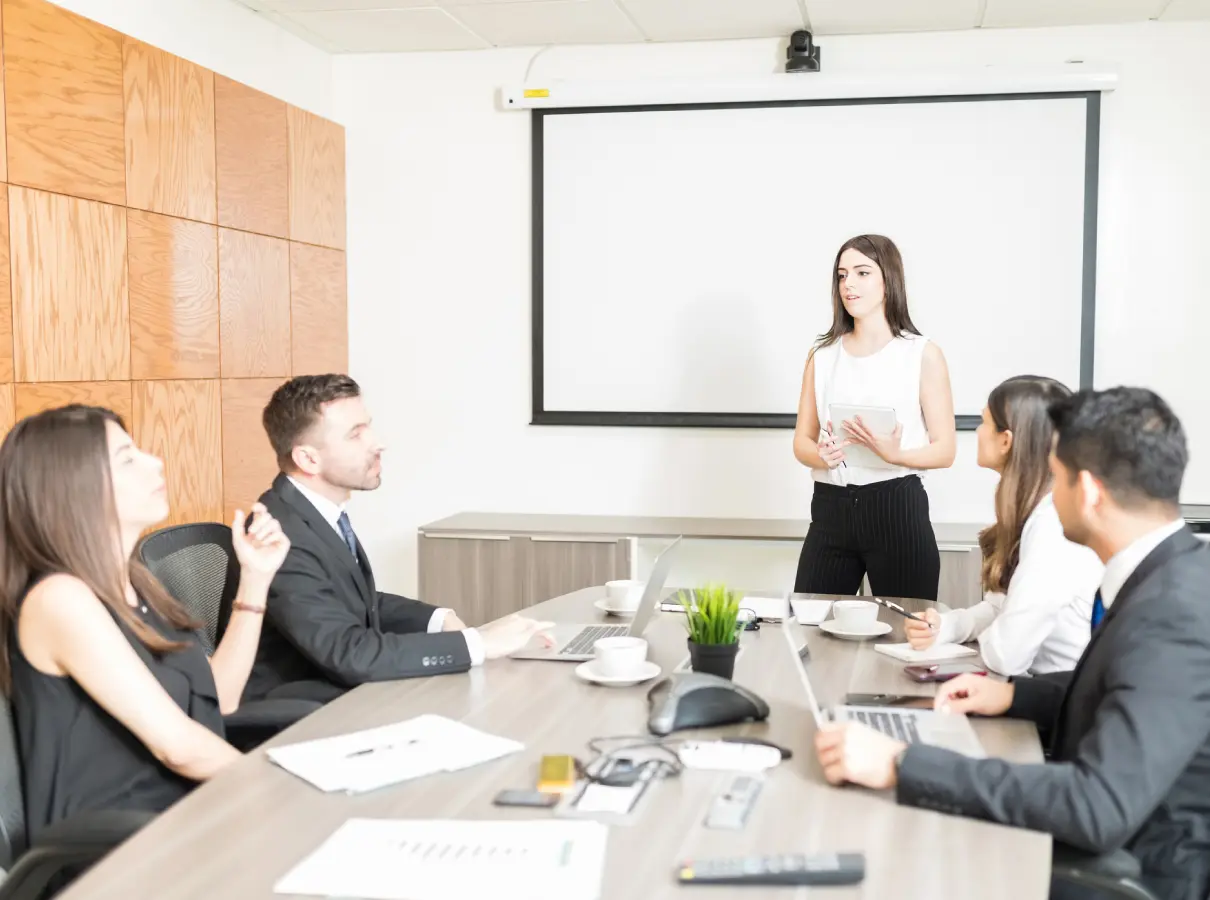 Businesswoman presenting to colleagues in a meeting room.