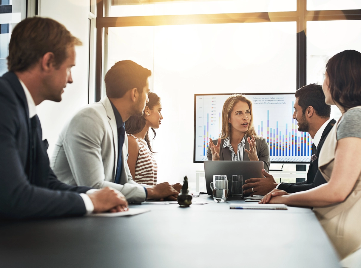 Business team in a meeting discussing ideas around a conference table.