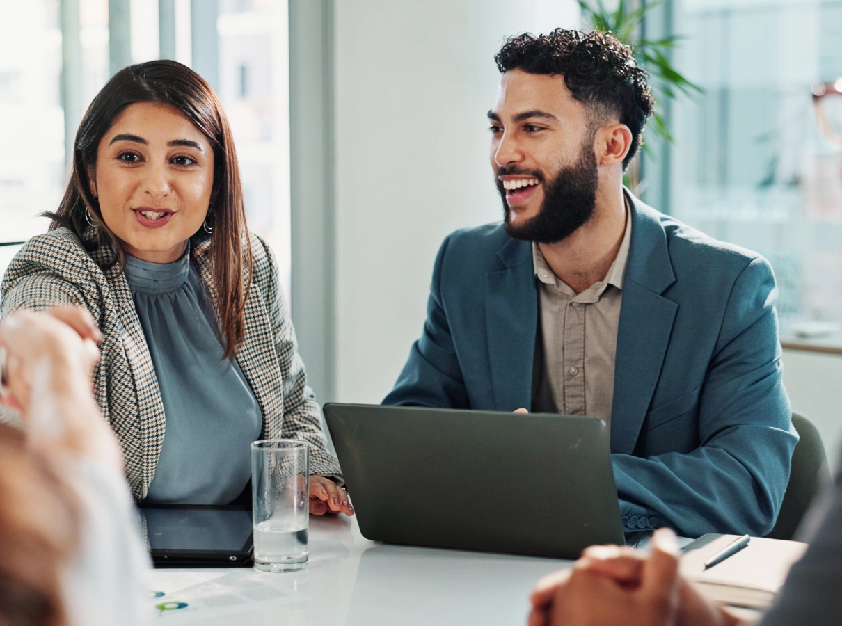 A man and woman in a business meeting with laptops and documents.