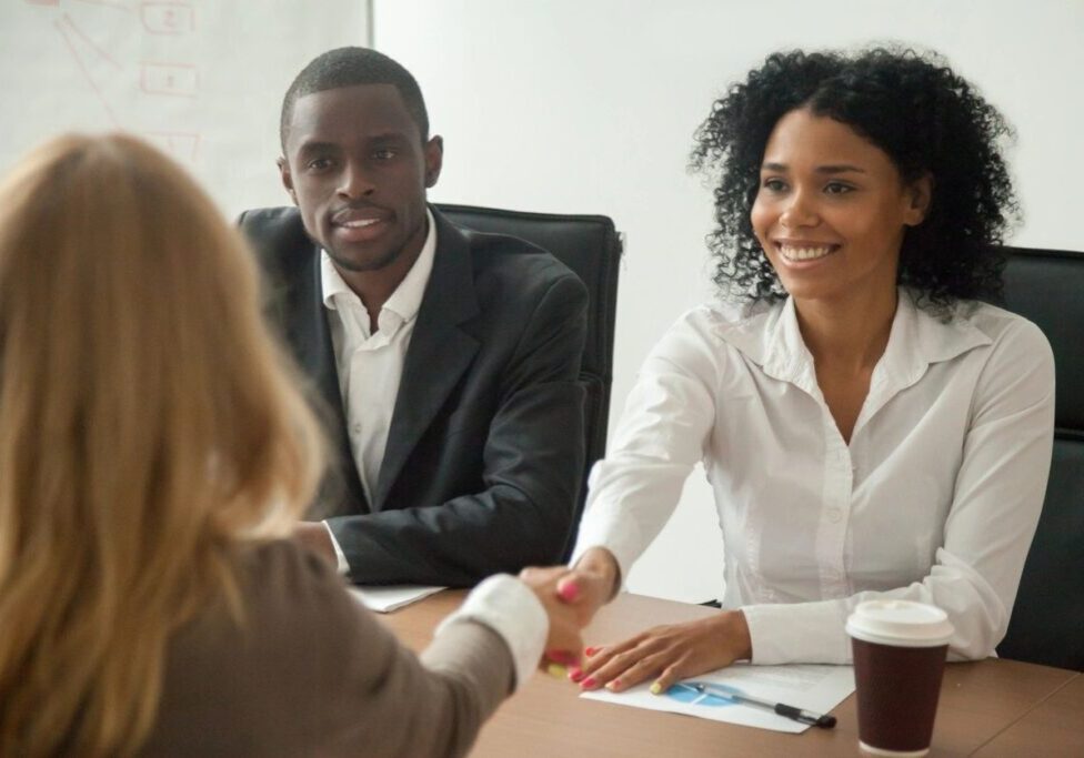 Two professionals shaking hands in a meeting.